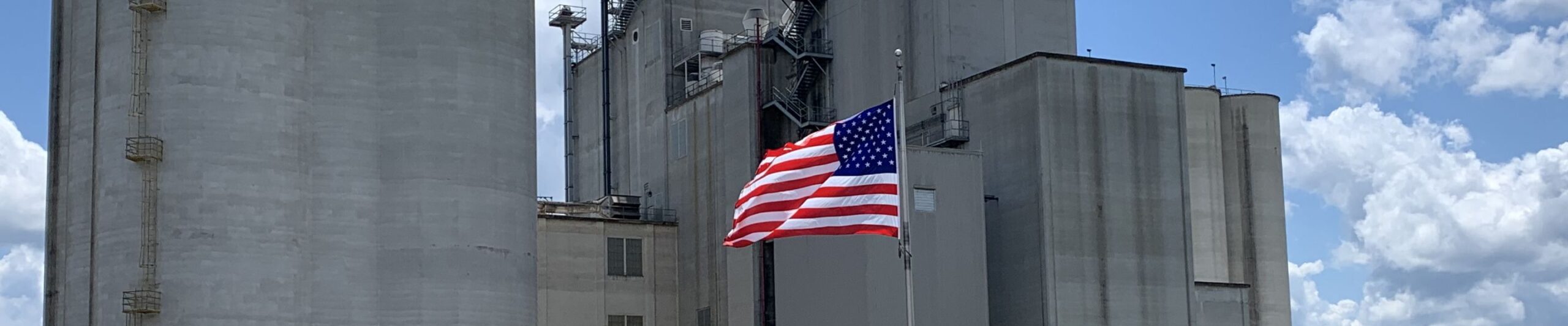 Image of a grain storage facility with the American Flag in front